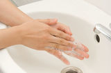 På billedet ses en håndvasknings-situation med hænder, der skyller sæbe af under rindende vand.